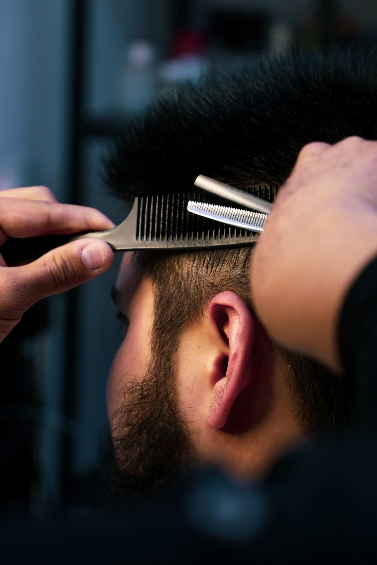 Barber knipt het haar boven het oor bij met een effileerschaar